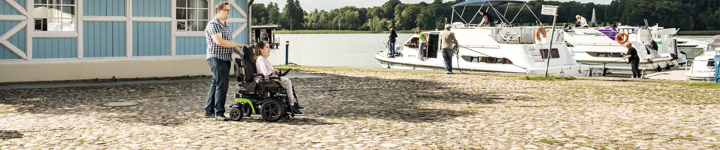 Layoutbild mit dem Elektrorollstuhl zum Bootsanleger an einem Fluß